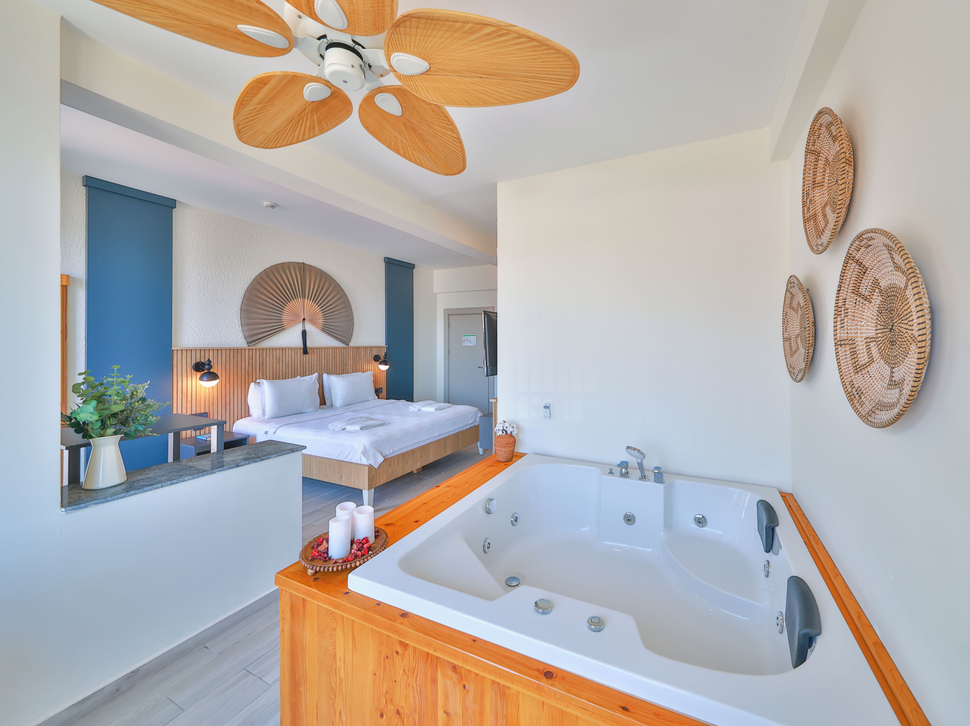 Una habitación de hotel moderna con una cama grande, una bañera y un ventilador de techo.