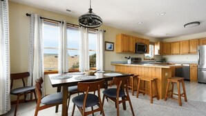 Een moderne keuken met houten kastjes, een centraal eiland en een eethoek met tafel en stoelen.