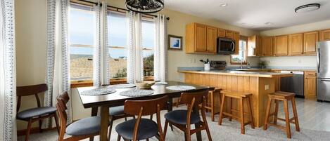 A modern kitchen with wooden cabinets, a central island, and a dining area with a table and chairs.