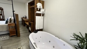 Een badkamer met een vrijstaand bad, een houten wastafelmeubel en een douchegedeelte.