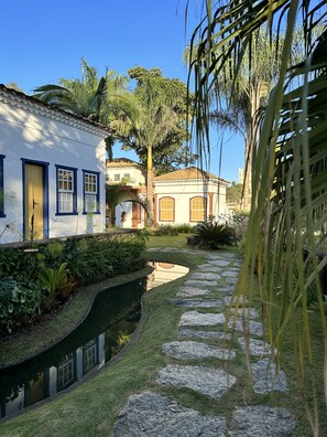 A serene courtyard with a stone pathway, a small water feature, and lush greenery.