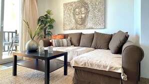 Ein Wohnzimmer mit einer Couch, einem Couchtisch, einem Buddha-Gemälde und einer Pflanze.