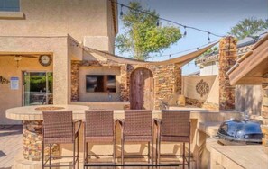 Enjoy dining and socializing in this outdoor patio area, featuring a round table and four chairs, a grill, and barbecue.