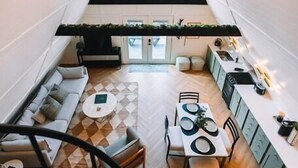 A spacious loft-style living area with a dining table, sofa, and kitchen area. - Secluded A-Frame Hocking Hills: Hot Tub, Fire Pit (South Bloomingville)