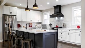 A modern kitchen with white cabinets, stainless steel appliances, a large island with bar stools, and pendant lighting. - Spacious 4BR/3.5BA Home Near UD, Oregon &DT Dayton (Dayton)