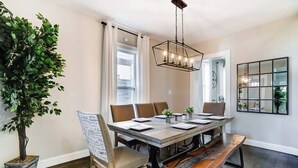 A dining room with a large table, six chairs, a bench, a hanging light fixture, and a potted plant. - Spacious 4BR/3.5BA Home Near UD, Oregon &DT Dayton (Dayton)