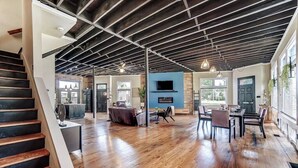 A spacious interior with a wooden staircase, a dining area with chairs, a kitchen, and a living space with a TV. - Dayton Loft close to DT, Oregon, UD (Dayton)