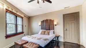 A bedroom with a bed, bench, bedside table, ceiling fan, and a door. - Dayton Loft close to DT, Oregon, UD (Dayton)