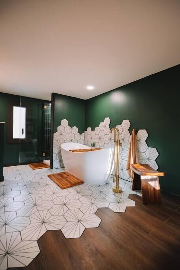 Ein modernes Badezimmer mit einer freistehenden Badewanne, geometrischen Wandfliesen und Holzboden.