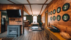 A wooden interior with a fireplace, dining table, and wall-mounted clocks.