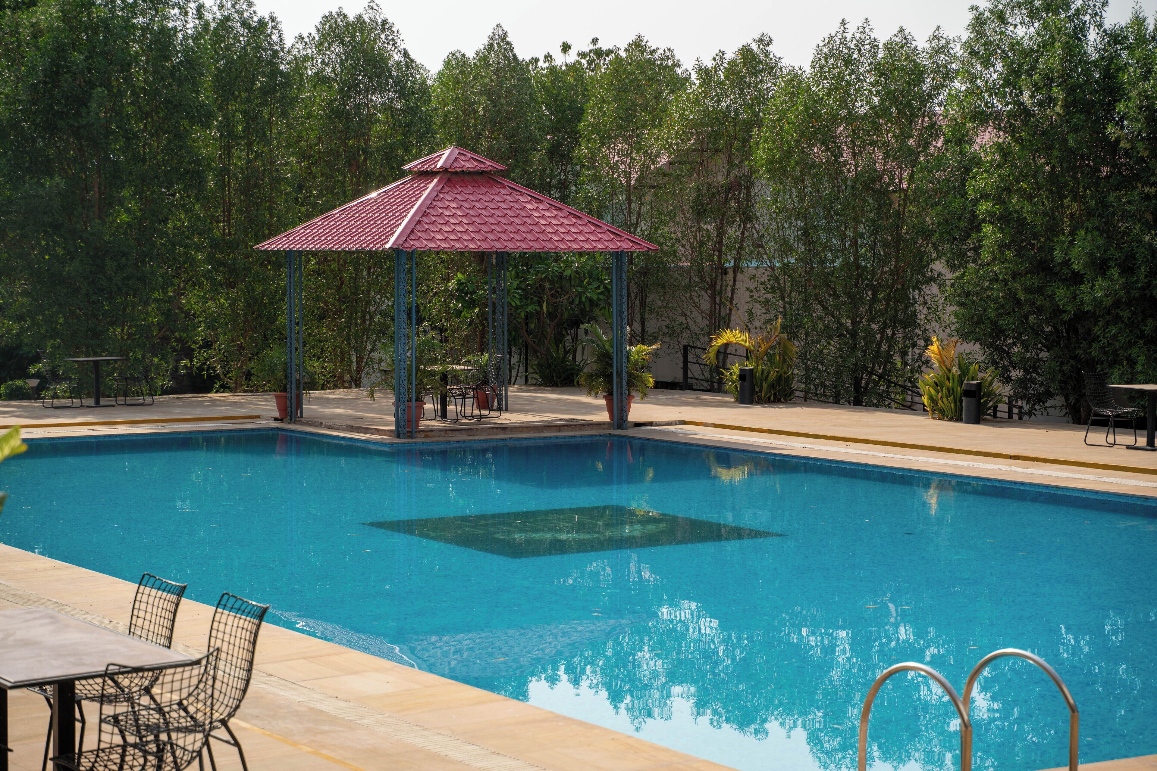 Ein Schwimmbad mit Gazebo, umgeben von Bäumen.