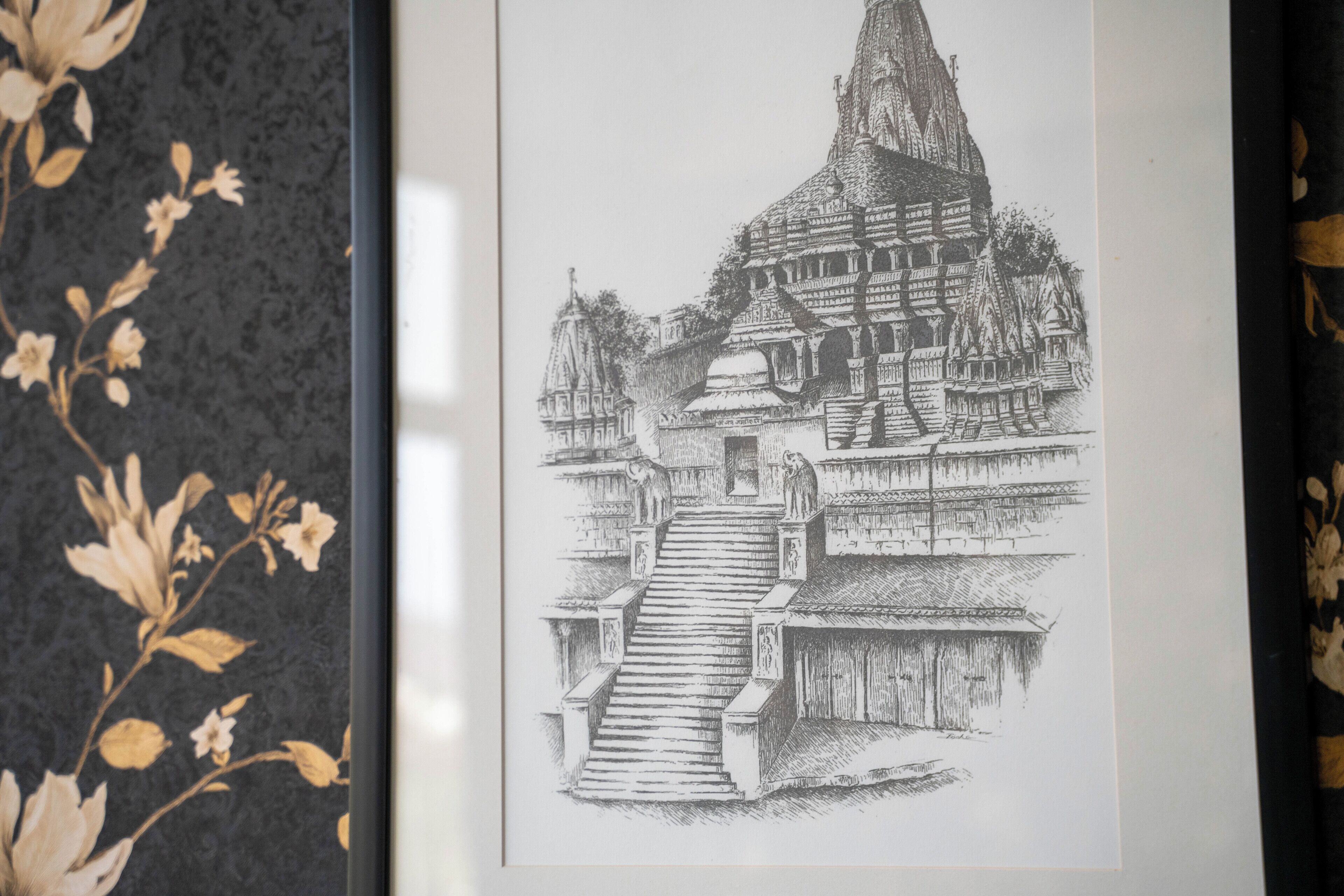 A framed black and white drawing of a temple complex with a central tower and a staircase leading up to it.