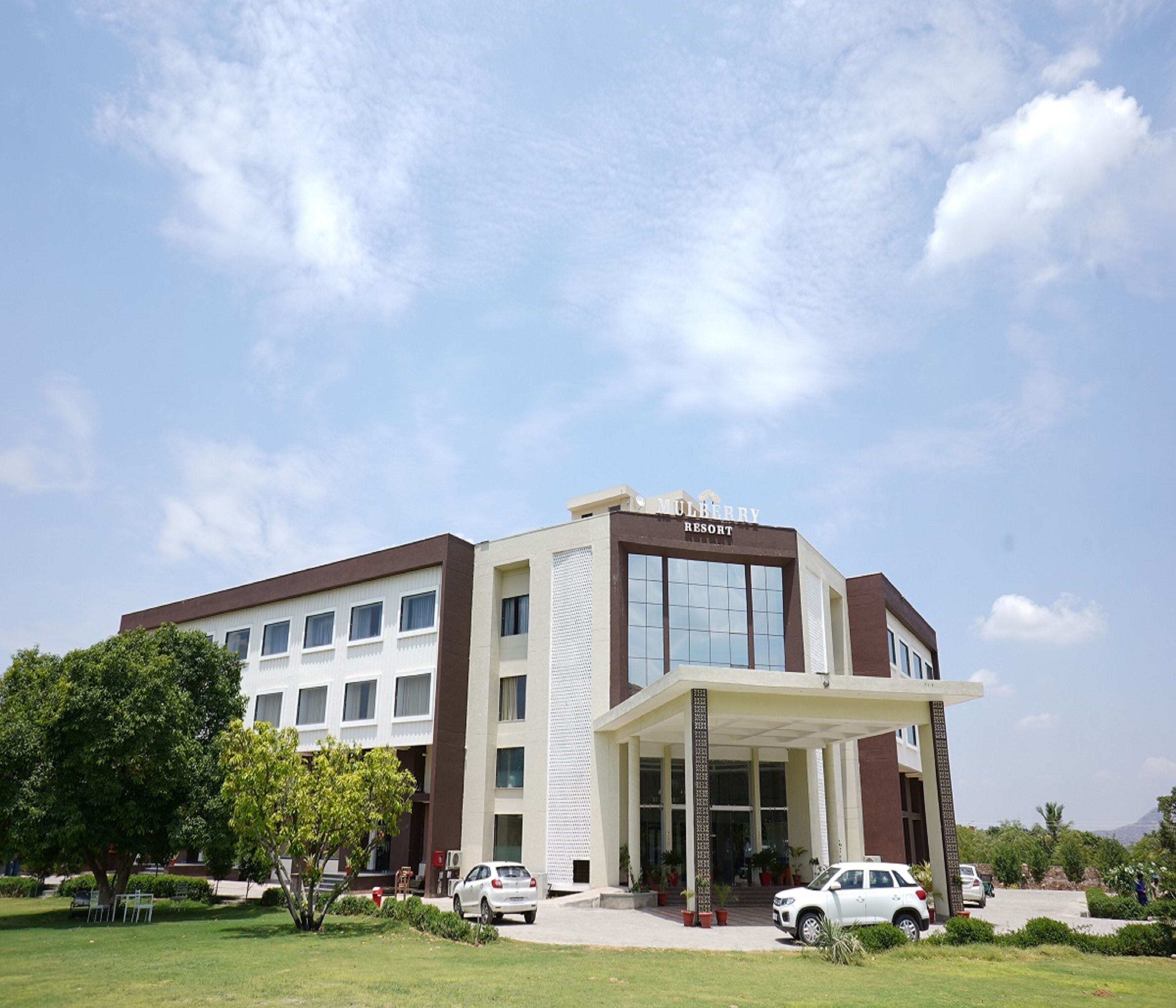 A modern hotel with a prominent entrance, multiple floors, and a clear sky.