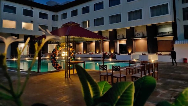 A hotel pool area with a covered seating area, multiple pools, and a building with balconies. - Bamboo Saa Mulberry Resort Pushkar (Pushkar)