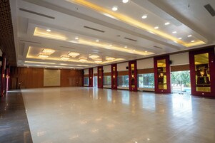 Un vestíbulo de hotel amplio y luminoso, con piso pulido, ventanas grandes y candelabros modernos.