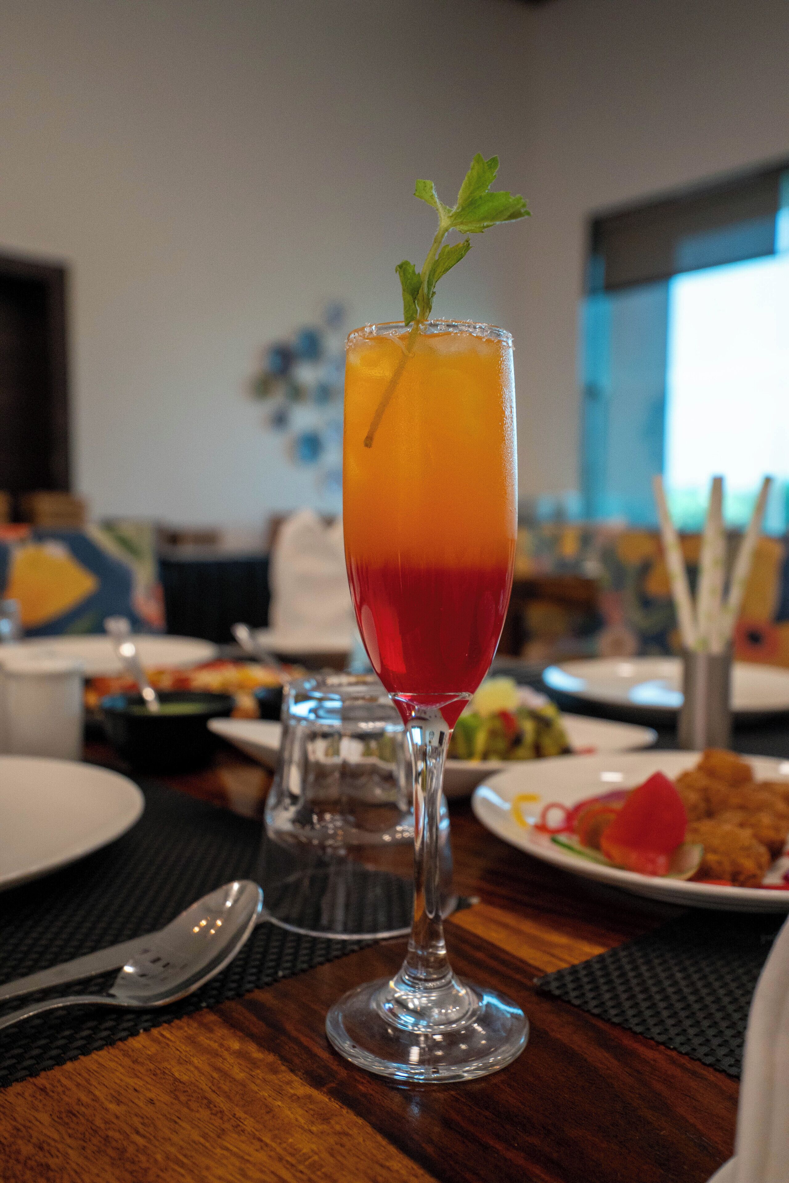 Ein Cocktailglas mit Farbverlauf auf einem Esstisch.
