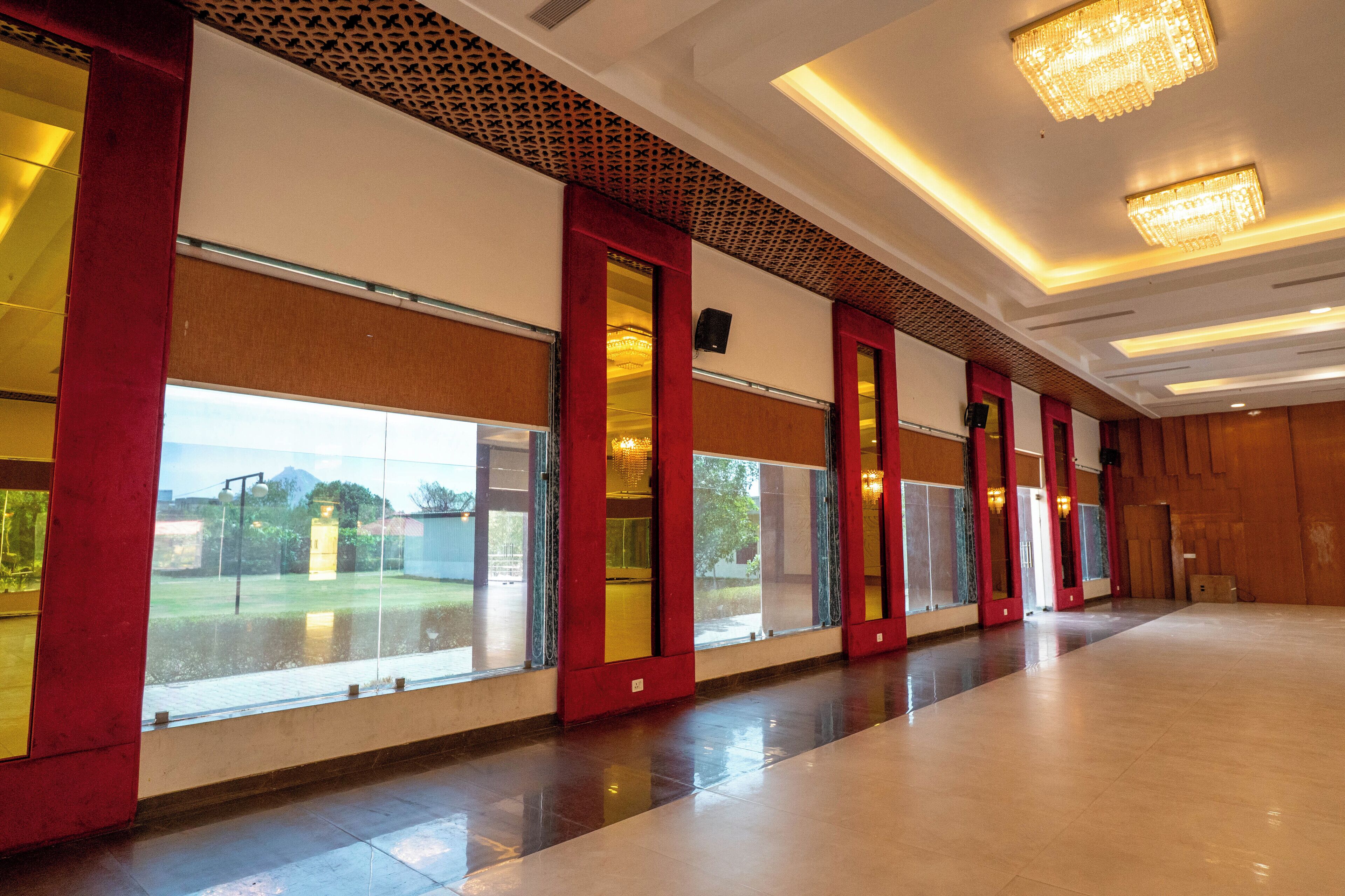 Un ampio corridoio con ampie finestre, porte a cornice rossa e moderne lampade.