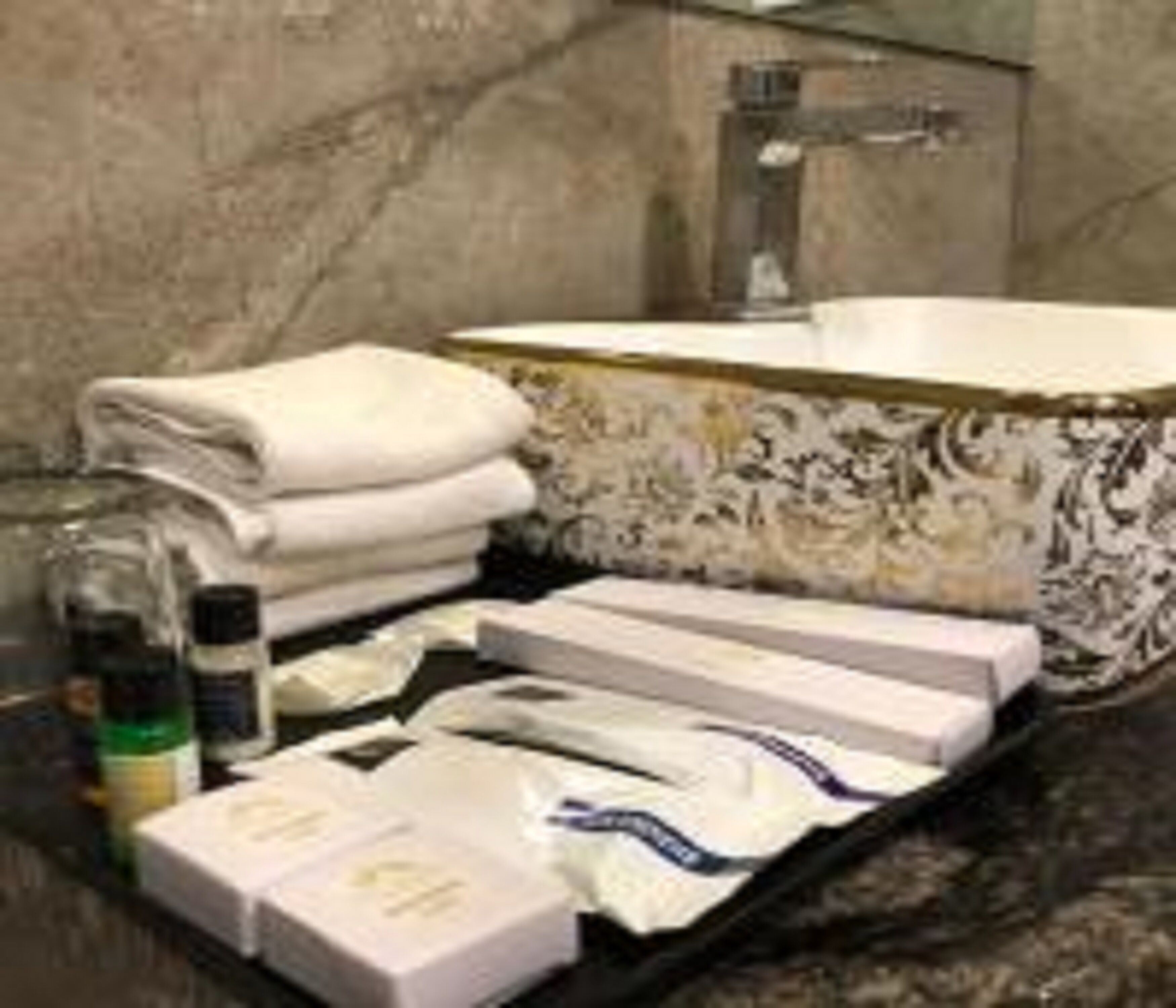 Un bagno con lavabo in marmo, asciugamani, articoli da toilette e specchio.