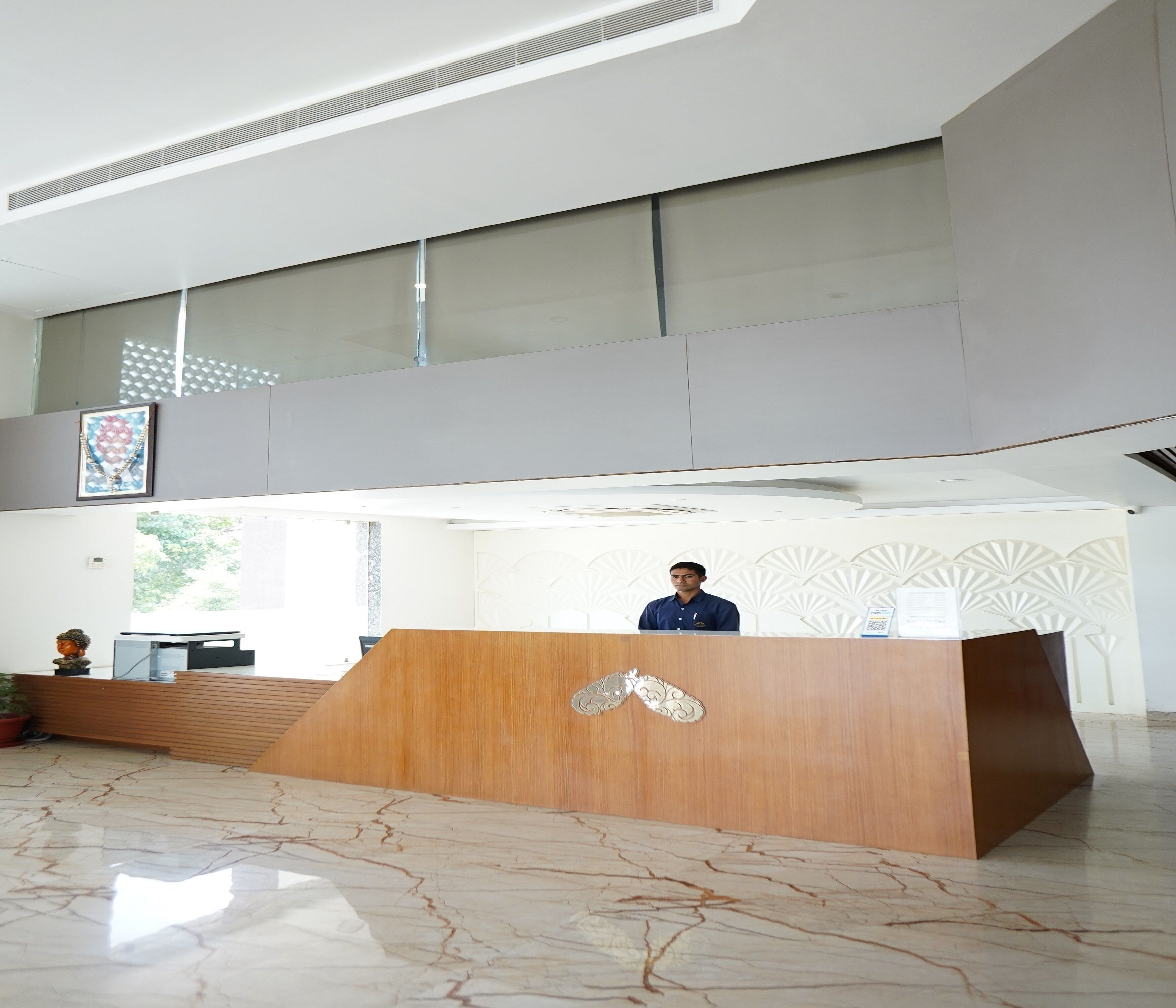 A reception area with a wooden desk, marble flooring, and a high ceiling with a skylight.