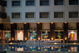A hotel with a swimming pool, outdoor seating, and multiple windows.