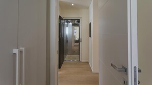 Un couloir moderne avec un plancher en bois menant à une pièce comprenant un lit et une salle de bain.