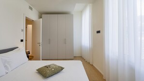Une chambre à coucher comprenant un lit, une armoire et une porte donnant sur une autre pièce.