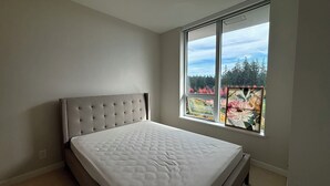 Ein Schlafzimmer mit großem Fenster, einem Bett und einer Deckenleuchte.