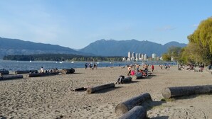 Ein Strand mit Menschen, Booten und Bergen im Hintergrund.