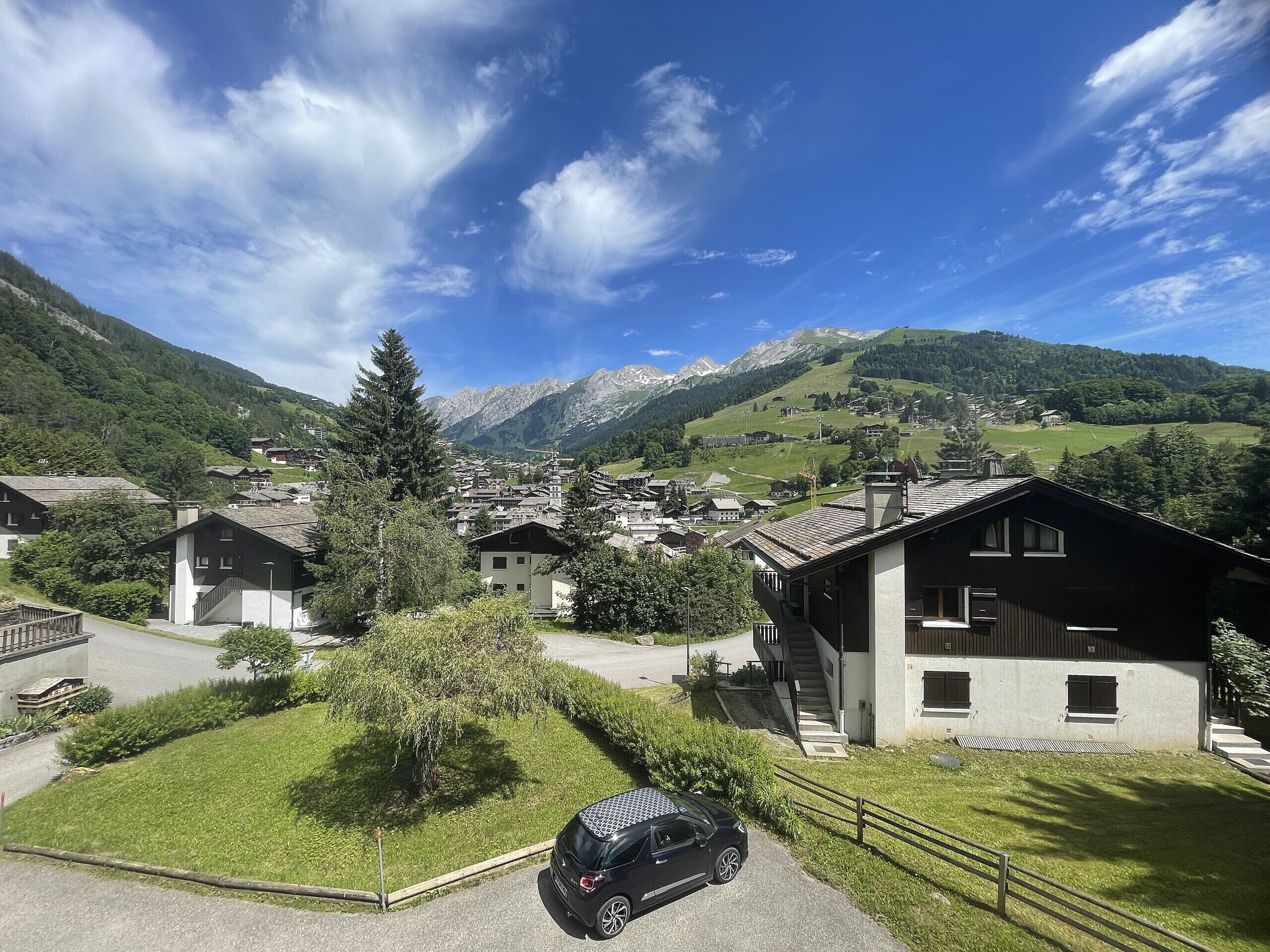 A residential area with houses, a car, and a mountain backdrop.
