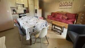Un espacio habitable compacto con una mesa de comedor, sillas, un sofá y un armario de madera.