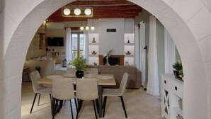 Un área de comedor con una mesa y sillas, un sofá y un televisor al fondo.