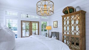 A bedroom with a large bed, a wooden cabinet, and a chandelier. - Stunning views of Lake Blackshear! (Warwick)