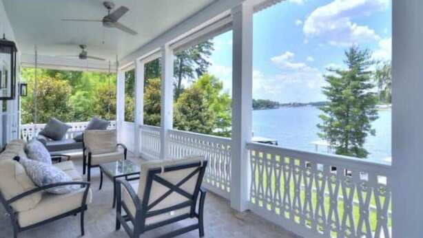 A covered patio with outdoor furniture, a view of a lake, and a white fence. - Stunning views of Lake Blackshear! (Warwick)