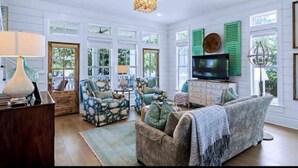 A spacious living room with a large television, multiple seating options, and a chandelier. - Stunning views of Lake Blackshear! (Warwick)