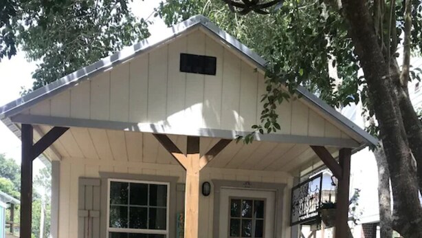 A wooden cabin with a porch, stone steps, and a small garden area. - Lush Couples Cottage w/ access to Waterfront Property, pier, pool & hot tub (Bacliff)