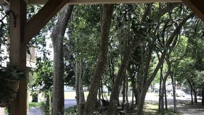 A covered outdoor area with a wooden fence, trees, and a paved path. - Lush Couples Cottage w/ access to Waterfront Property, pier, pool & hot tub (Bacliff)