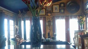 Ein Essbereich mit einer großen Vase voller roter Blumen auf einem Tisch, umgeben von Stühlen und einer Kristallleuchter.