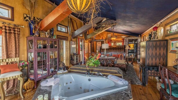 Ein luxuriöses Badezimmer mit einer großzügigen Badewanne, Holzboden und verschiedenen Dekorationsgegenständen.