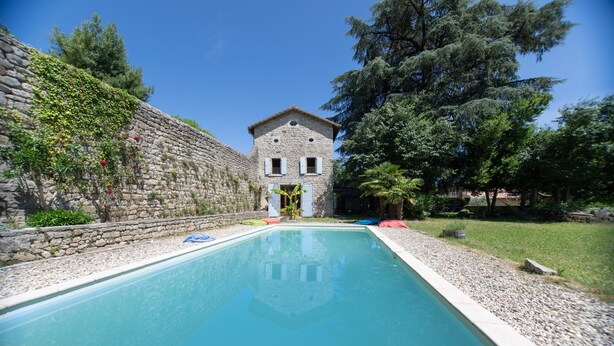 A swimming pool with a stone wall and a building in the background.