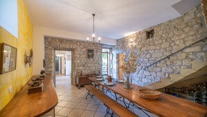 A spacious kitchen with a stone wall, wooden benches, and a dining table set for four.