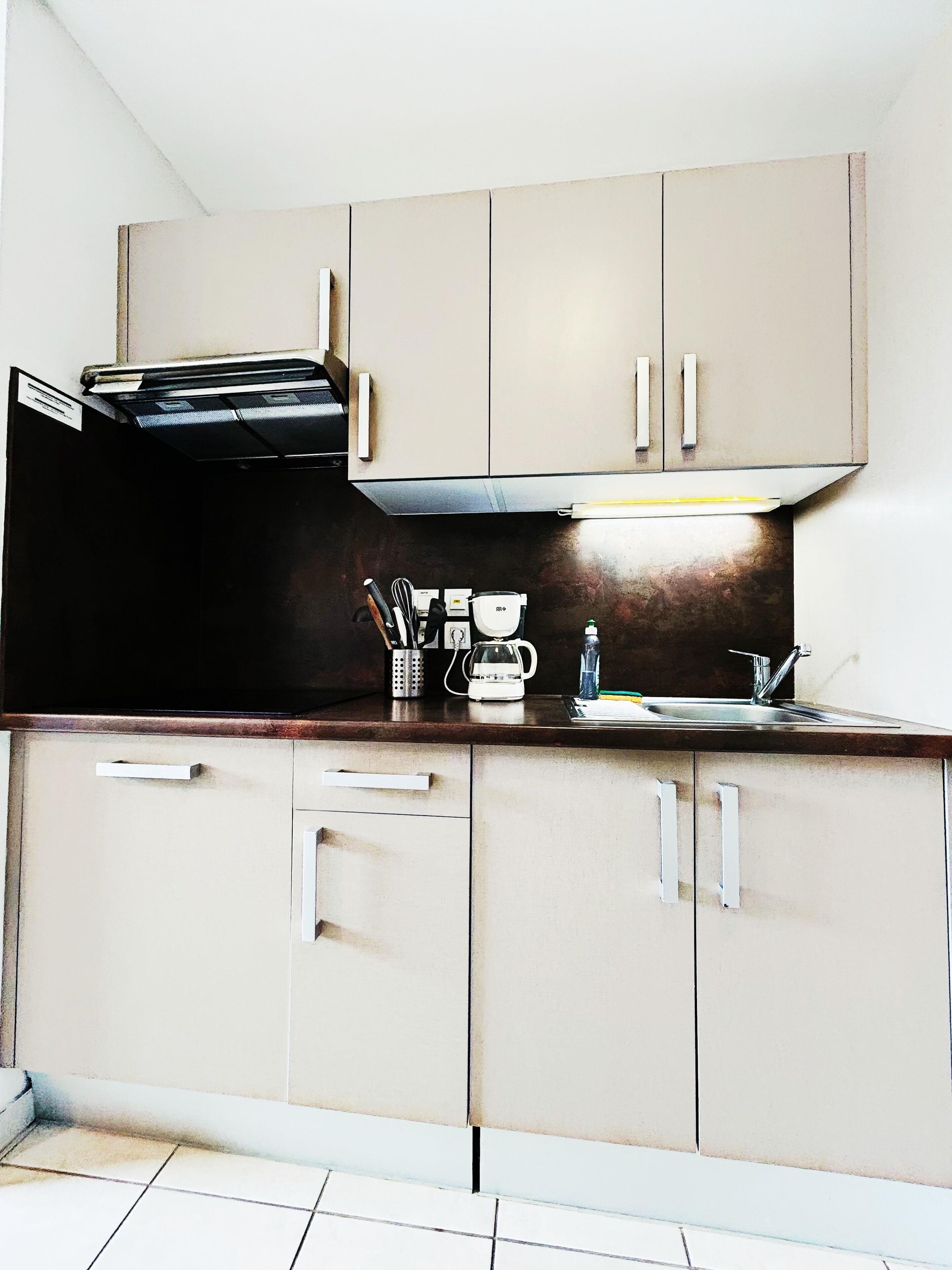 A kitchen with cabinets, a countertop, a coffee maker, and a sink.