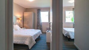 Une chambre d’hôtel avec un lit, une table de chevet, une armoire et une fenêtre avec des rideaux.