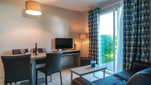 Un salon moderne comprenant un coin repas, un téléviseur à écran plat et un balcon agrémenté de rideaux.