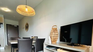 Un salon moderne comprenant un coin repas, un téléviseur à écran plat, une lampe en fibres naturelles et un design minimaliste.