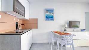 A modern kitchen with a built-in stove, white cabinets, and a dining area with a table and chairs.