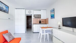 A modern apartment with a kitchen, dining area, and a living room with a sofa and TV.