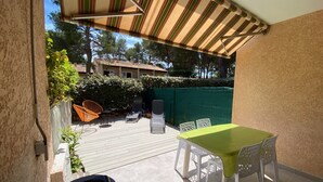 A patio with a table and chairs, a striped awning, and a view of a building with a tiled roof.
