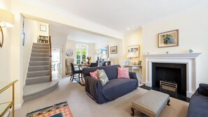 A spacious living room with a dark blue sofa, a patterned rug, and a fireplace.
