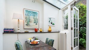 A dining area with a table set for breakfast, a lamp, and framed artwork on the wall.