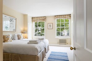 A bedroom with a double bed, two bedside tables, a radiator, and two windows with curtains. - Delightful rental house in Kensington (London)